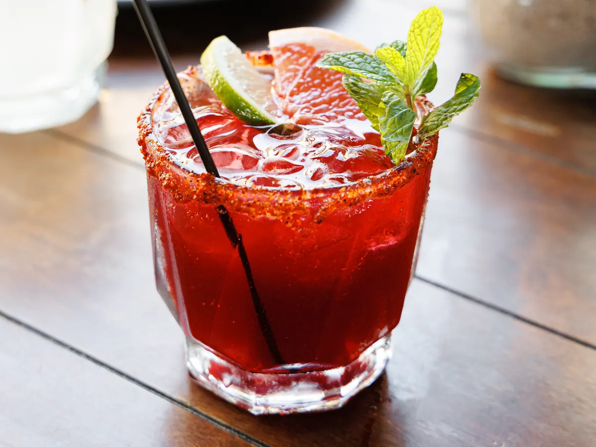 Cóctel rojo con hielo, limón y hierbabuena